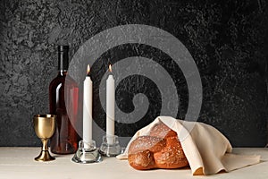 Traditional challah bread with wine and glowing candles on dark background. Shabbat Shalom photo