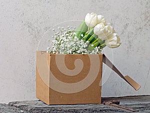 Shabby chic white tulips in cardboard box.