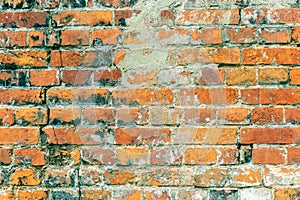 Shabby grungy wall of an old red brick with cracks and cement, background in urban loft style
