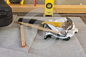 Shabby hammer, ruler and protective gloves at a construction site. construction and renovation concept