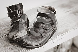 Shabby old black leather shoes are on the wooden table