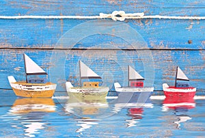 Shabby toy boats in a row on blue background - on the sea - holiday, sailing, cruising concept photo