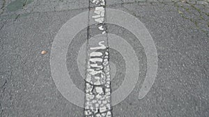 Shabby white arrow on cracked old gray asphalt. Road marking of the direction of movement