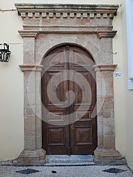 Shabby wooden door in medieval sentury style of a white old house on the street of a old greec town.