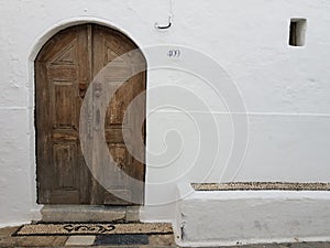 Shabby wooden door of a white old house on the street of a old greec town.