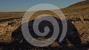 Shade of a car moving by the country road in the wide wasteland landscape at sunset time