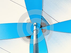 Shade sails in white in front of a blue sky.