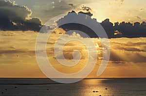 Shade of sunlight behind dark cloud before sunset over sea and s