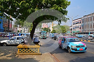 Shade under a big tree with vehicles on Sule Pagoda Road in Yangon, Myanmar