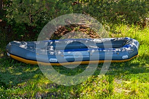 In the shade under the trees large inflatable rafting boat near the river in the Altai Mountains. Extreme sports