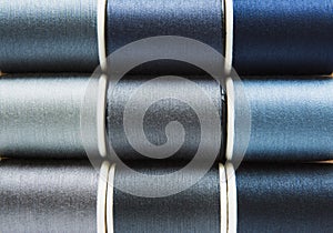 Shades of gray and blue sewing threads background closeup