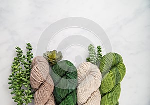 Shades of green and tan yarn on marble
