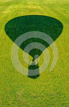 The shadow of a balloon flying over a green meadow
