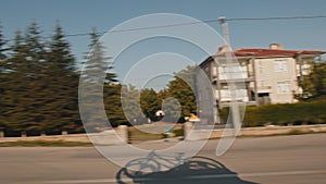 The shadow of bicycles mounted on the roof of a car falls on the asphalt road