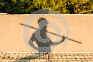 shadow of builder in protective helmet carrying metal structure at construction