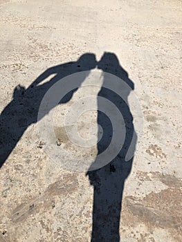 Shadow of couple on asphalt walking with hands up. Concept of relationship. Shadows of couple in love on a walk. Couple