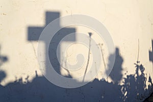 Shadow of a cross on a grave in a Greek cemetery at dawn