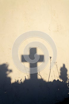 Shadow of a cross on a grave in a Greek cemetery at dawn