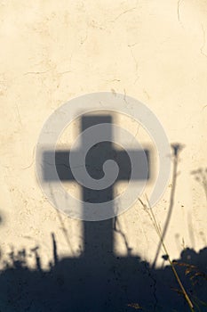 Shadow of a cross on a grave in a Greek cemetery at dawn