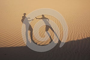 Shadow in dunes with thirsty man