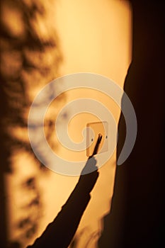 Shadow of hand turning off light switch