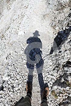 shadow of the hiker with hat and his boots to walk in the stony