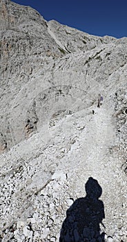 shadow of hiker on pebble and stone path on european alps