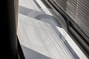 Shadow and light through blinds window on window sill. Morning light and shadow