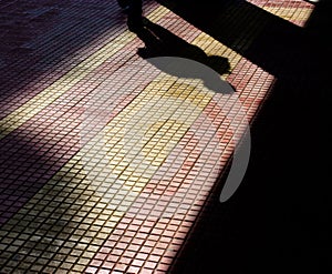 Shadow of a man and a column on patterened sidewalk