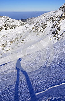 The shadow of a man doing winter trekking in the mountains