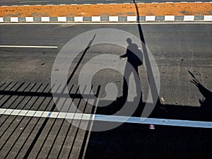 the shadow of a man going on a asphalt road
