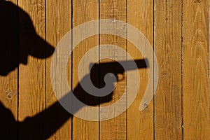 Shadow of a man with a gun on a wooden fence