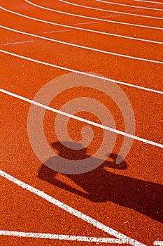 Shadow of man on red running track. Sport concept