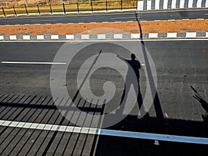 the shadow of a man showing route on a road