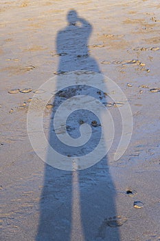 Shadow on man taking photograph on sand beach