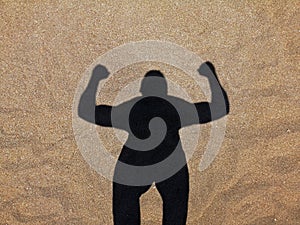 Shadow of muscle man on the beach, silhouette of strong man in the sand