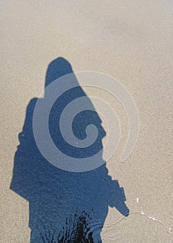 the shadow of a Muslim woman on the sand of the beach