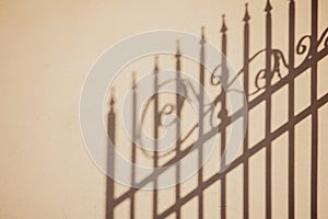 Shadow of an ornate fence on a yellow plaster wall