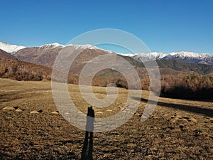 Shadow of a person in a cold field in the Pyrenees in front of a snowy mountain in winter