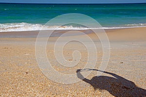 Shadow of person with hands making a heart shape on the beach