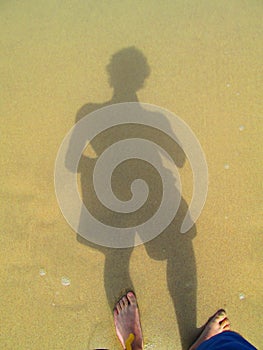 Shadow of a person on sand by the sea