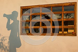 The shadow of a photographer casted by the light of sunset on a wall