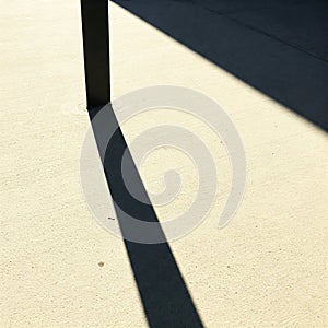 The shadow of a pole on the sunny asphalt.