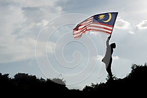 Silhouette of a boy holding the malaysian flag celebrating the Malaysia independence day photo