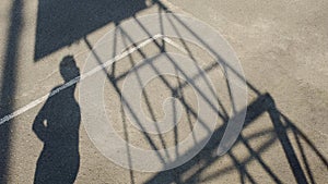 Shadow of sportsman standing on stadium and looking at basketball hoop, sport