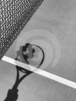 Shadow of tennis balls on the racket on hard court by the net. Tennis net shadows on tennis yellow balls.