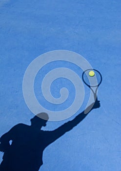 Shadow of Tennis Player Serving on Blue Court