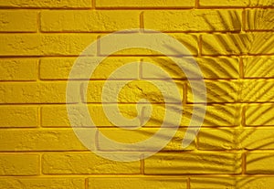 Shadow of tropical palm leaf on yellow brick wall, space for text