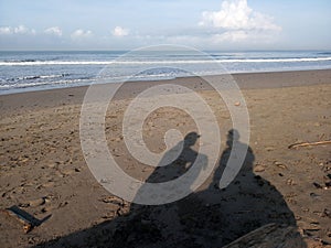 Shadow of two best friends sitting on wood outdoor in the beach. About friendship concept