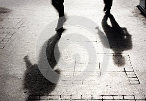 Shadow of two person on patterened sidewalk